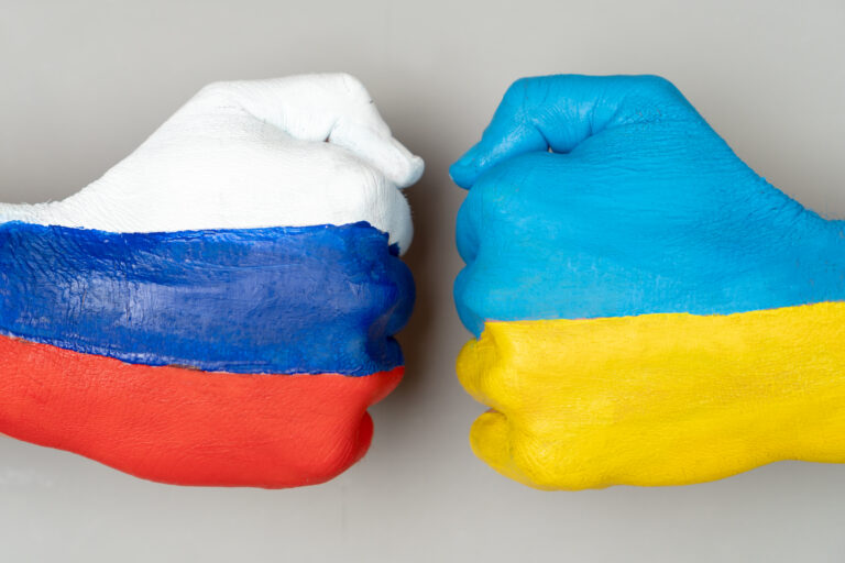 Flags of ukraine and russia flag on hands punch to each others o