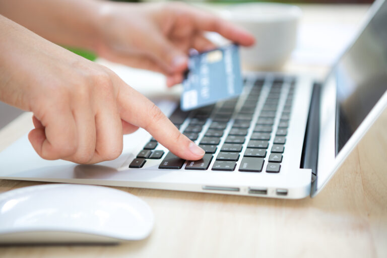 Hands holding a credit card and using laptop computer for online