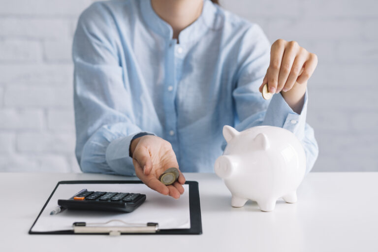 businesswoman-showing-coins-with-white-piggybank-desk