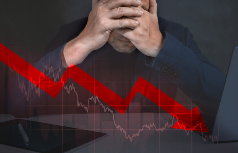 Depressed business man looking down at falling red arrow. desperate about losing money of crisis, recession, inflation.