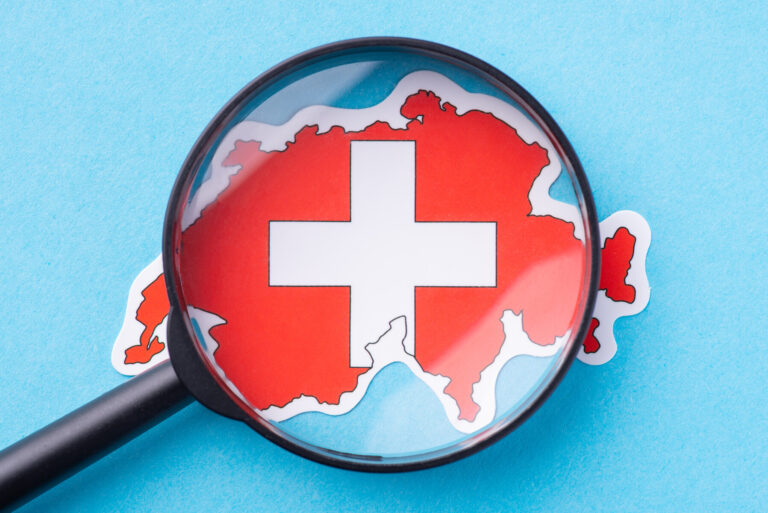 Magnifying glass on map of Switzerland. Concept of closer look the European country, study its culture traditions and religion