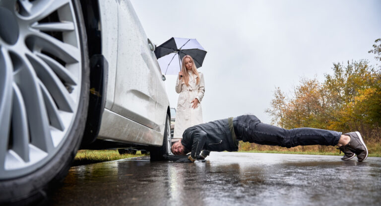 Charming young woman watching how man fixing car wheel.