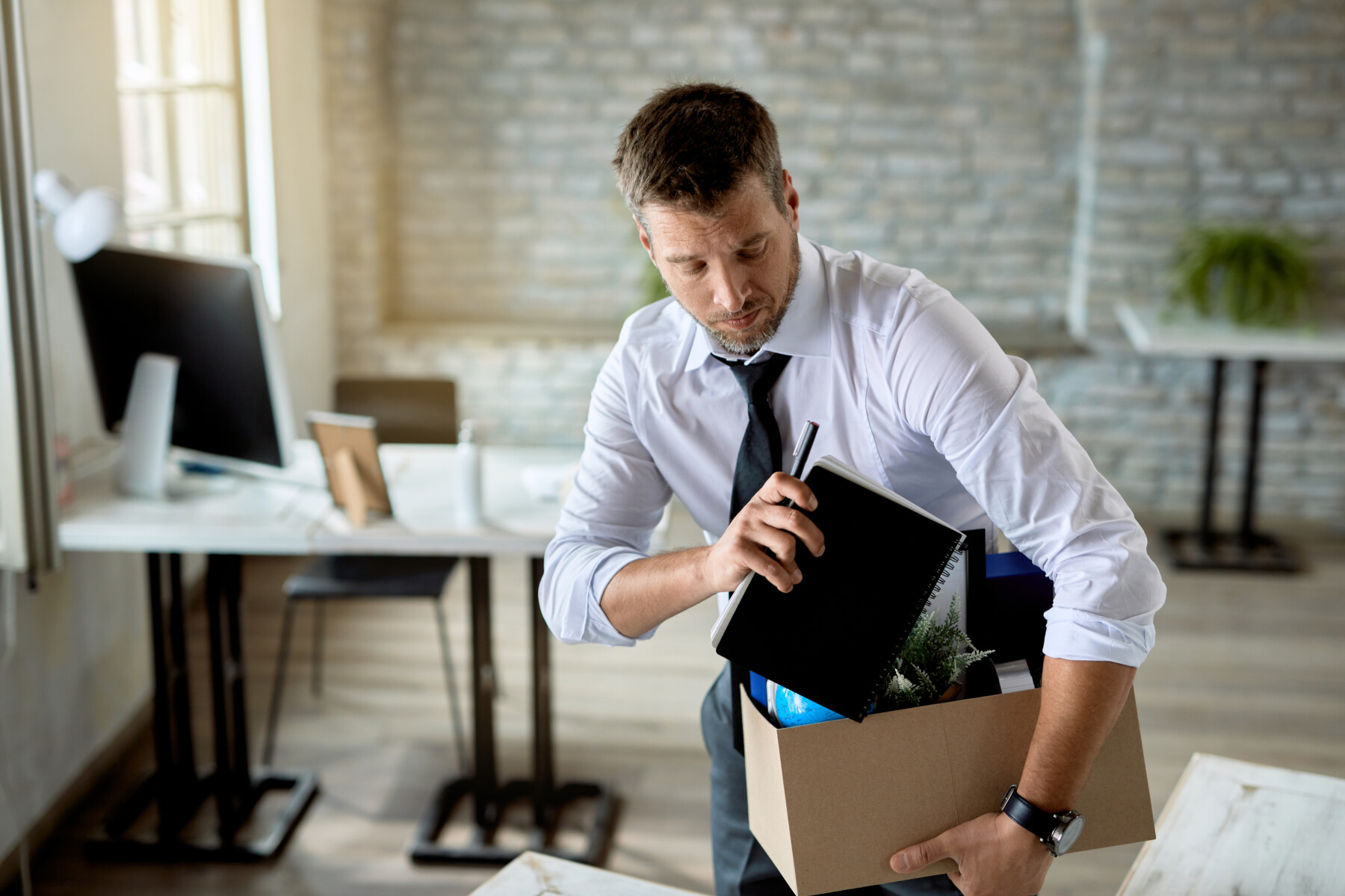 Male entrepreneur packing his belongings after being fired at wo