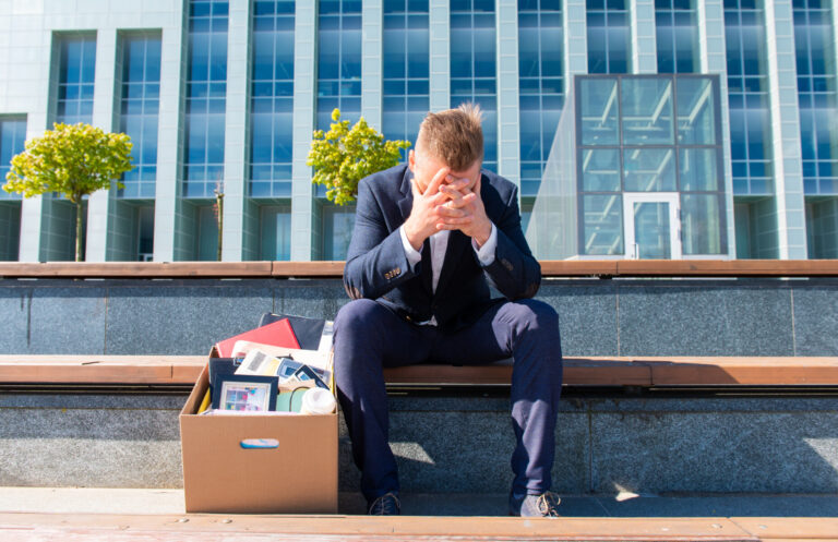 Stress jobless concept former employee sitting with his belongings stuffed box him