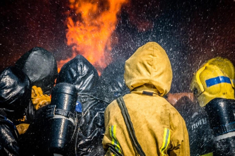 Rear view firefighters spraying water fire