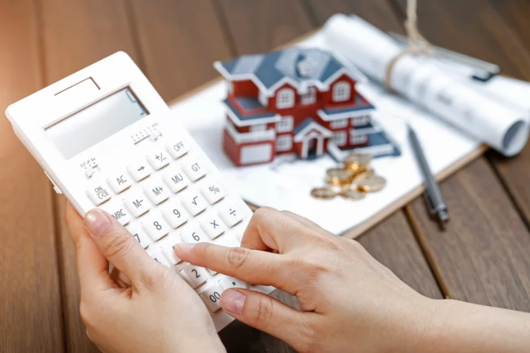 Female hand operating calculator front villa house model