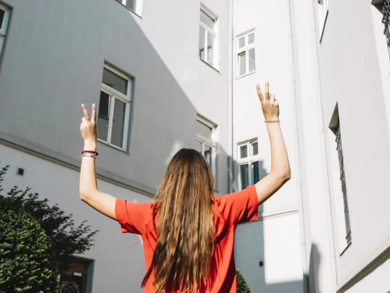 Rear view woman making peace gesture near building