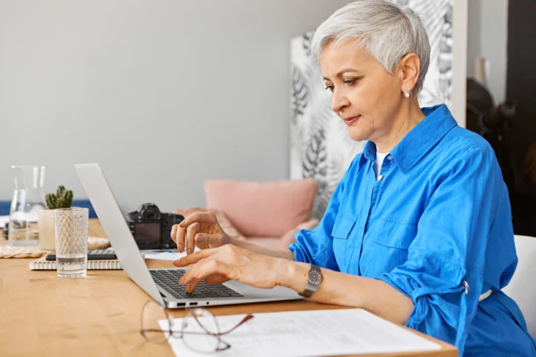 People job occupation age employment indoor image beautiful gray haired female retirement looking remote work using portable computer mature woman photographer typing laptop